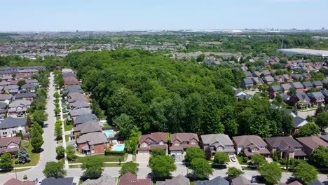 Drone-flying-up-over-a-forest-in-the-middle-of-a-Mississauga-neighborhood-on-a-summer-day