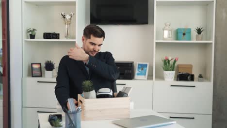 The-portrait-depicts-a-young,-handsome,-serious-man-who-has-arrived-at-a-new-workplace-and-is-unpacking-his-stuff-on-the-desk,-dressed-in-business-attire-and-expressing-happiness-at-his-promotion
