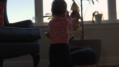 Toddler-girl-walks-around-living-room-with-her-puzzle-toy---from-behind