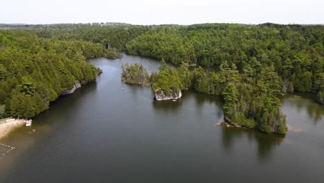 Aerial-shot-flying-up-over-a-sunny-lake-with-a-beach-in-Guelph