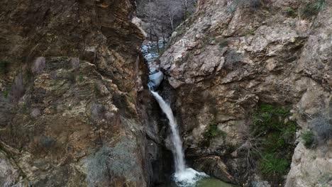 Eaton-Canyon-Falls-reveal-from-behind-a-tree-on-a-cliff-showing-hikers-and-a-raging-waterfall-in-Angeles-National-Forest