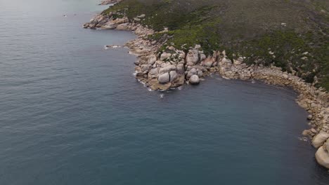 Drone-aerial-slow-fall-and-pan-over-beautiful-blue-water-and-white-rocks-on-a-sunny-day-in-Wilsons-Promontory