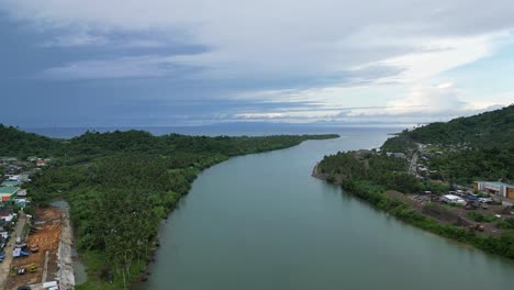 Epic,-Cinematic-Aerial-Shot-of-massive-river-between-lush-Jungles-and-rural-communities-with-stunning-cloudscape