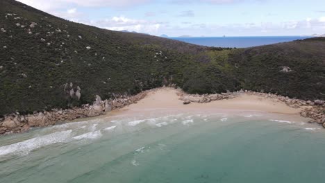 Drone-aerial-slow-turn-over-beautiful-light-blue-water-and-green-mountain-on-a-sunny-day-in-Wilsons-Promontory