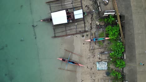 Top-Down-Aerial-View-of-Bangka-Boats-parked-on-white-sand-beach-with-crystal-clear-waters-in-Catanduanes,-Philippines