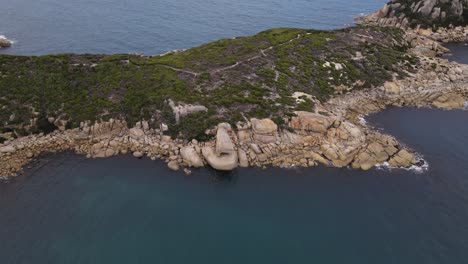 Drone-aerial-slow-pan-and-turn-over-beautiful-blue-water-and-green-mountain-on-a-sunny-day-in-Wilsons-Promontory