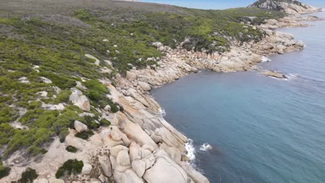 Drone-aerial-rising-and-pan-down-over-beautiful-blue-water-and-white-rocks-on-a-sunny-day-in-Wilsons-Promontory