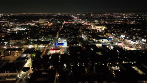 Vista-Aérea-Volando-A-Través-De-Hollywood-Los-Angeles-Noche-Paisaje-Urbano-Horizonte-Iluminado