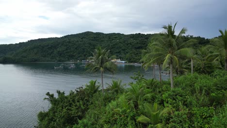 Erhebt-Sich-Und-Zeigt-Eine-Luftaufnahme-Der-Philippinischen-Tropeninsel,-Die-Ländliche-Fischerdörfer-Und-üppige-Dschungel-Entlang-Des-Ruhigen-Meereswassers-Enthüllt