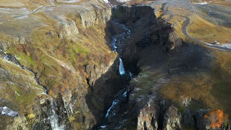 Waterfalls-in-Rocky-Iceland-Canyon-at-Base-of-Snowy-Mountain,-Aerial