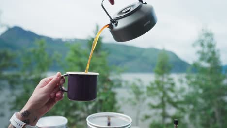 Gießen-Sie-Heißen-Kaffee-Aus-Einer-Metallteekanne-In-Eine-Tasse