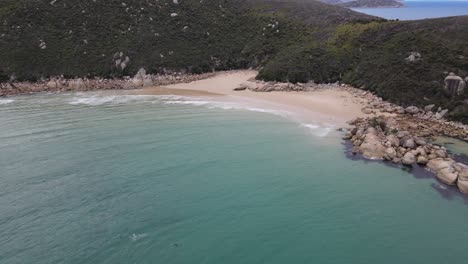 Drone-aerial-pan-down-over-beautiful-blue-water-and-white-rocks-on-a-sunny-day-in-Wilsons-Promontory