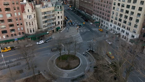 Aerial-view-tilting-over-a-park,-toward-traffic-in-middle-of-streets-in-Manhattan,-spring-in-New-York