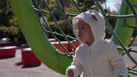 Young-toddler-girl-explores-outdoor-play-structure-park-on-sunny-brisk-autumn-day---medium-shot