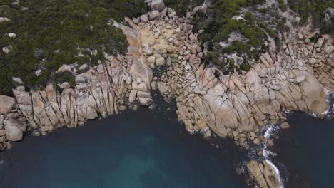 Drone-aerial-looking-down-and-spin-over-beautiful-blue-water-and-white-rocks-on-a-sunny-day-in-Wilsons-Promontory
