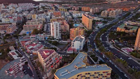Aerial-view-of-Los-Cristianos-city-resort-buildings-and-traffic-road,-circle-pan