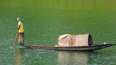 An-Asian-fisherman-paddles-his-boat-on-Surma-River,-capturing-the-serene-beauty-of-nature-and-the-peaceful-simplicity-of-traditional-fishing
