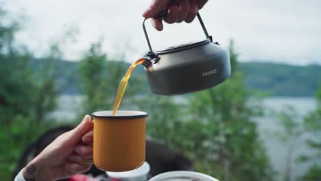 Hand-Pouring-Hot-Brewed-Coffee-Into-Mug-Outdoor-During-Break-From-Road-Trip
