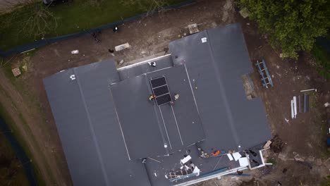 Unrecognizable-workers-install-solar-panels-on-roof-of-new-house