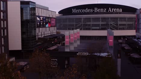 Drone-flight-between-buildings-toward-Mercedes-Benz-Arena-in-Berlin,-Germany