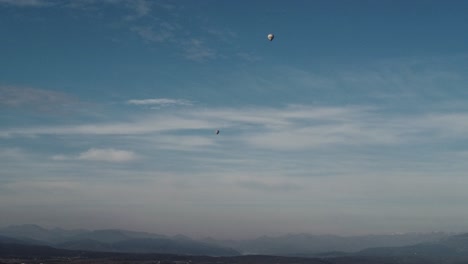 Aerial-shot-of-two-tiny-air-balloons-under-a-light-cloudy-sky