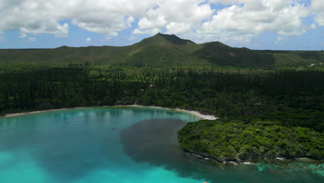 The-lagoon-in-the-crystal-clear-water-of-Kanumera-Bay-on-the-Isle-of-Pines---pull-back-aerial-flyover