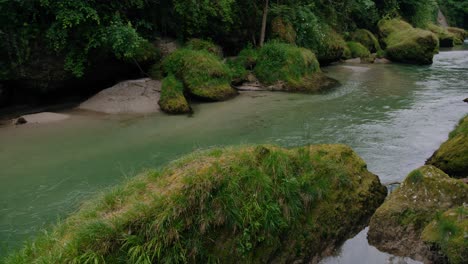a-creek-flowing-slowly-through-a-narrow-canyon-surrounded-by-trees-and-grass-in-Austria
