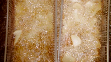 Top-down-close-up-of-potato-dippers-deep-fried-in-oil-in-baskets