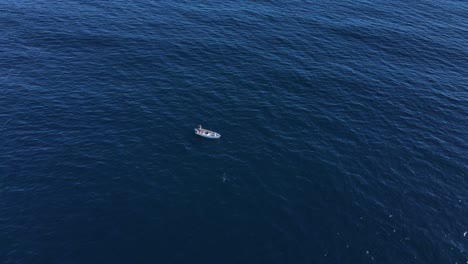 Rising-aerial-view-of-lone-fishing-vessel-in-deep-blue-pacific-open-ocean-water