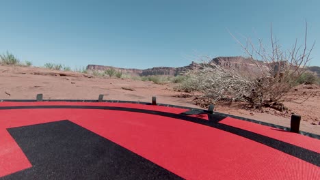 Drone-point-of-view-while-landing-on-the-red-ground-with-the-huge-cliffs-on-background