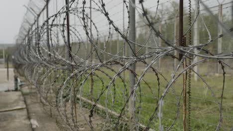 High-Security-Razor-Wire-Fence-inside-a-Prison,-Barbed-Wire-Metal-Fence-along-the-Border-Protection,-Smooth-CInematic-Shot