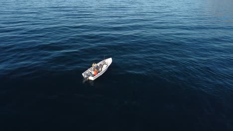Aerial-orbit-around-fishermen-adjusting-gear-on-boat-in-open-ocean