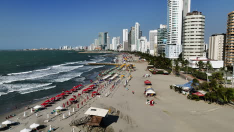 Ascending-aerial-view-of-people-on-the-Playa-De-Bocagrande-beach,-in-sunny-Cartagena,-Colombia