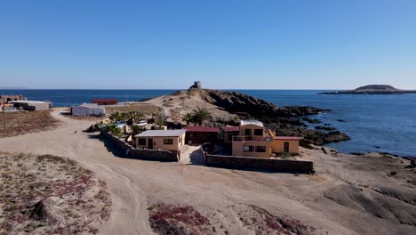 Aerial-dolly-of-coastal-sea-villa-on-rocky-mexican-beach-by-blue-ocean-water