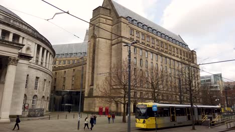 Manchester-Central-Library-next-to-Manchester-Town-Hall-with-tram-moving-past,-Manchester,-England,-UK