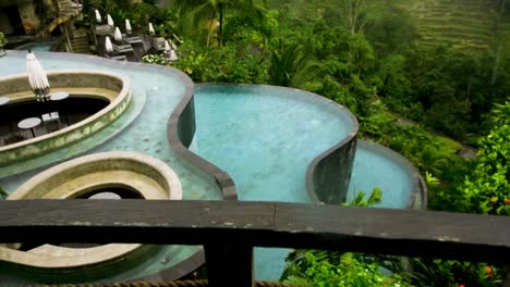 Handheld-dolly-up-on-rainy-luxury-pools-looking-towards-terraced-forest
