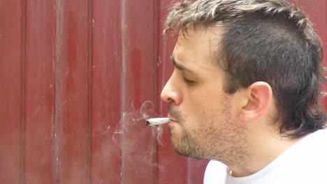 Eine-Person-Zündet-Sich-Vor-Einer-Roten-Wand-Eine-Marihuana-Zigarette-Oder-Einen-Cannabis-Joint-An