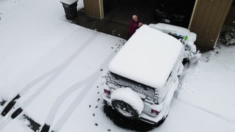 A-man-cleaning-the-powdery-snow-off-his-vehicle