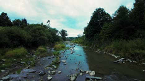 A-low-and-fast-drone-flight-over-a-beautiful-mountain-river-between-green-trees-in-summer