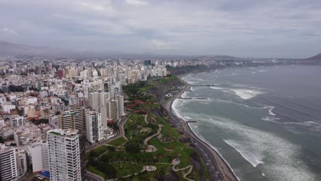 Coastal-area-called-"Costa-Verde"-with-green-hills,-tall-buildings-to-the-left-and-pacific-ocean-on-the-right