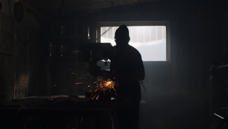 Masked-person-grinds-metal-with-an-angle-grinder-throwing-sparks-over-their-metal-shop