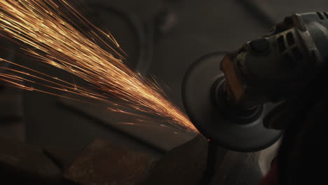 Sparks-fly-in-a-circle-as-angle-grinder-bevels-edge-of-metal-in-vice-on-workshop-bench