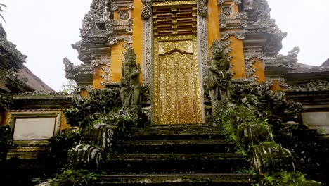 Tilt-up-reveal-of-ornate-gold-Saraswati-Temple-steps-in-jungle-and-cloudy-sky