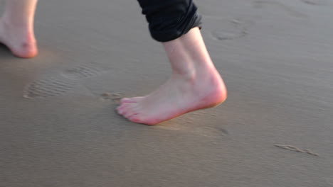Feet-Of-A-Caucasian-Man-Walking-Barefoot-At-The-Sandy-Shoreline