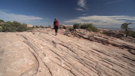 Einsame-Wanderin-In-Der-Wüste-Von-Utah,-Die-Auf-Felsigem-Boden-Läuft,-Rückansicht,-Zeitlupe
