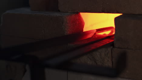Blacksmith-turns-a-red-hot-metal-hook-in-a-furnace-oven-in-a-workshop