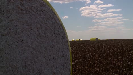 Cotton-Bales-In-Protective-Wrap-at-Cotton-Field,-Pull-Back-Drone-Shot