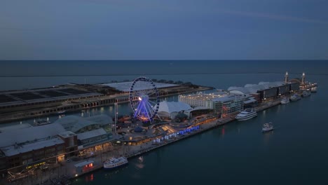 Aerial-view-of-a-boat-passing-the-Centennial-Wheel-at-the-Navy-Pier,-moody-evening-in-Chicago,-USA