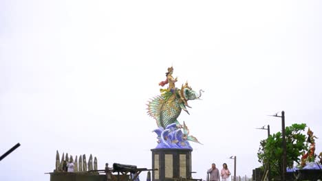 Statue-Von-Gajah-Mina-Am-Strand-Von-Pererena-Mit-Touristen,-Die-An-Einem-Regnerischen-Tag-Vorbeigehen