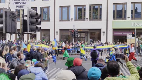 St-Patrick's-Day-parade-passing-on-streets-of-Cork-city,-Ireland,-with-Ukraine-group-and-flags